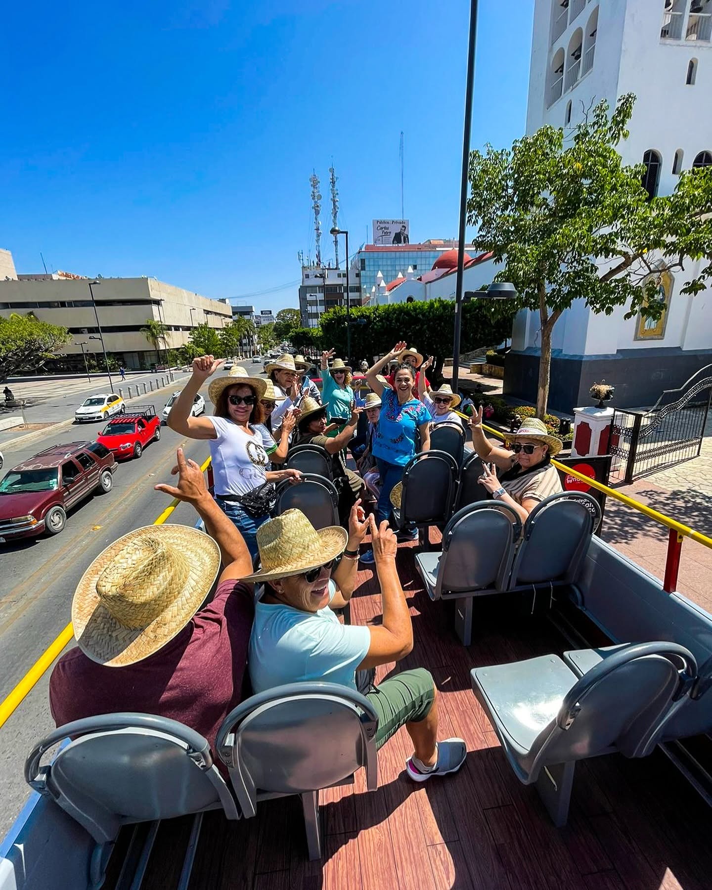 Viajeros con sombreros disfrutando el segundo piso del Andabús